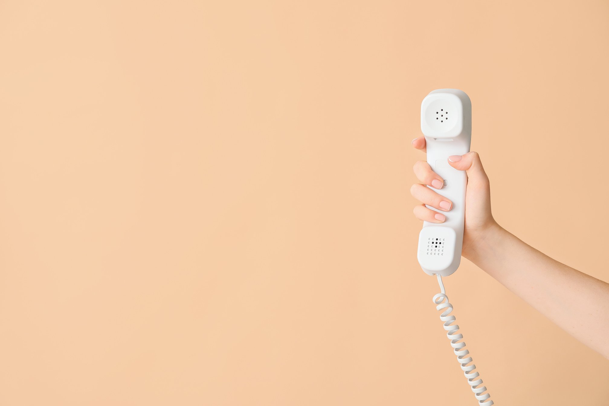 Hand of Woman with Corded Phone on Color Background